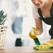 Close-up on housewife with yellow gloves and cloth cleaning a table at home